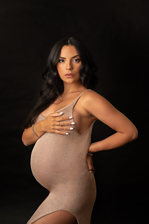 Empowered fine art maternity photo of woman in revealing fashion-forward sheer knit dress with high-end editorial styling.