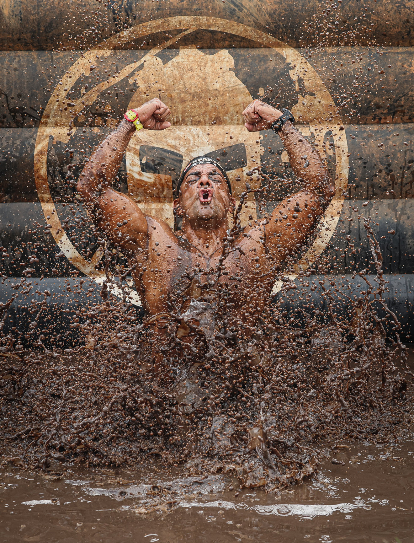 Obstacle course racer charging through mud and water