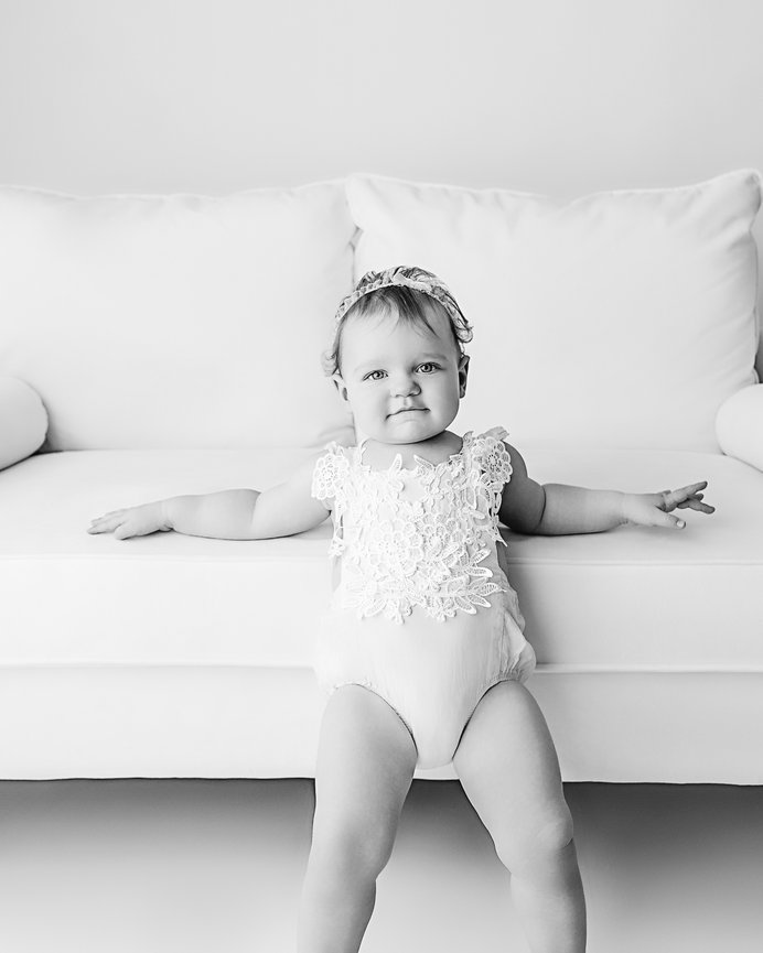 One-year milestone portrait before cake smash on white couch in Jersey Shore natural light studio