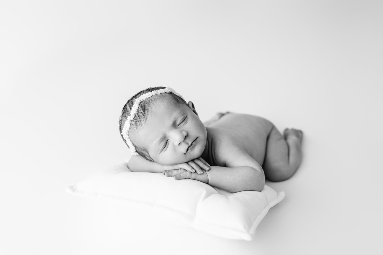 Striking black and white image of newborn laying on a little pillow, captured in Monmouth County studio
