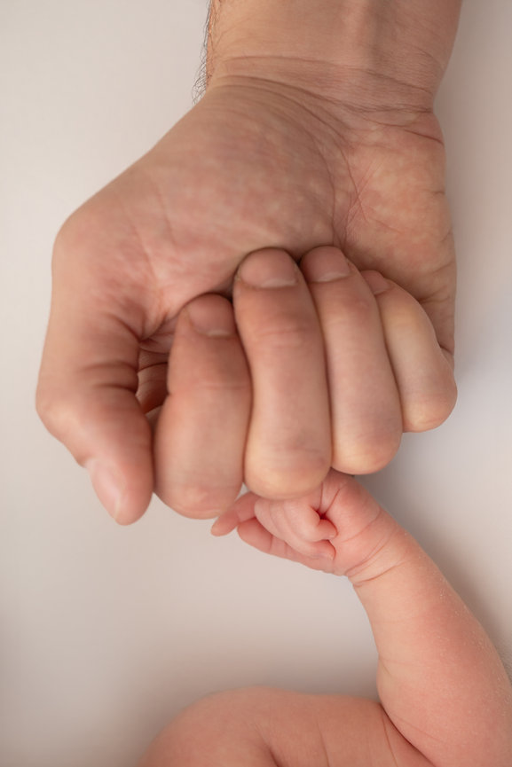 Lifestyle image of baby and parent knuckle-to-knuckle connection in Kristin Baker’s all-white Manasquan studio