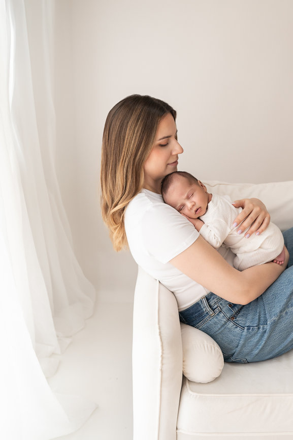 Mother whispering to newborn on white couch