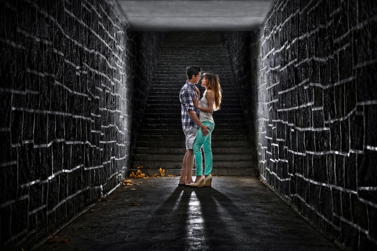 Couple embracing in a dark stone tunnel.