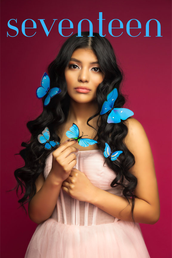 Fort Worth senior magazine-style portrait with young woman holding blue butterflies on a bold red backdrop.