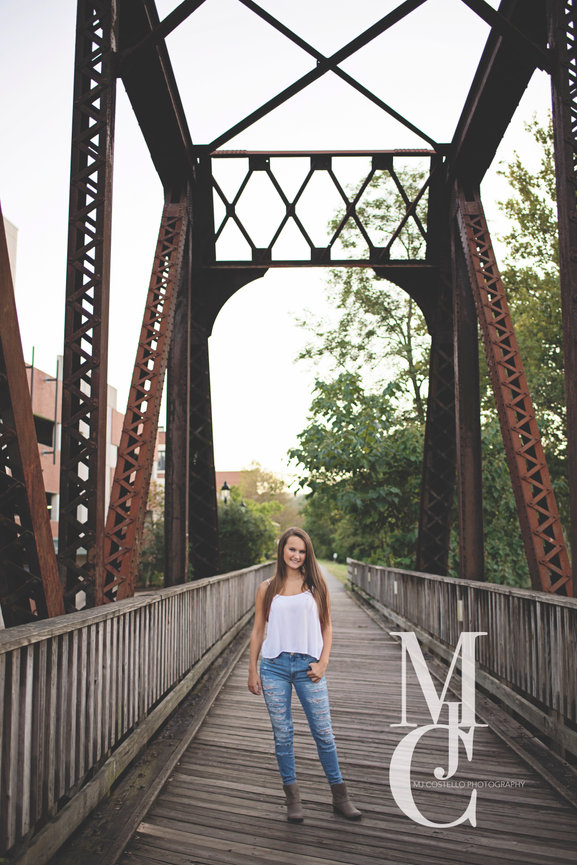 Young woman standing on a railroad bridge with metal beams overhead