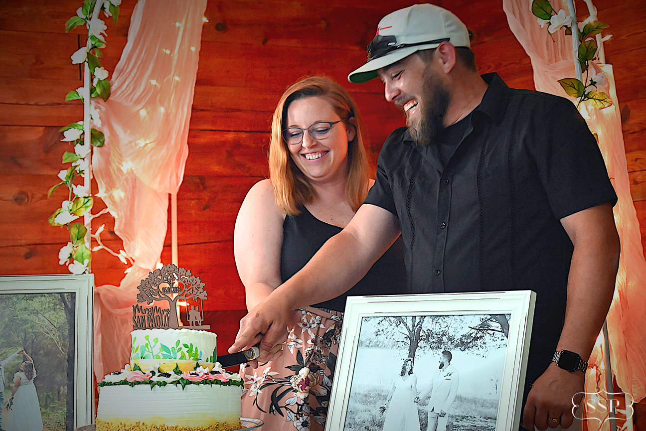 Couple standing beside framed photos at a decorated event display