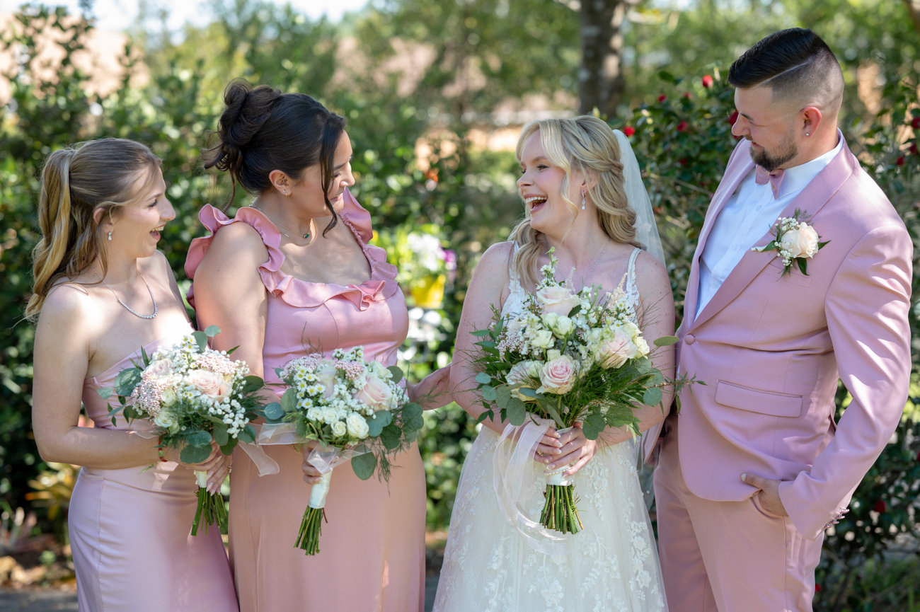 Bride and bridesmaids posing with the groom outdoors.