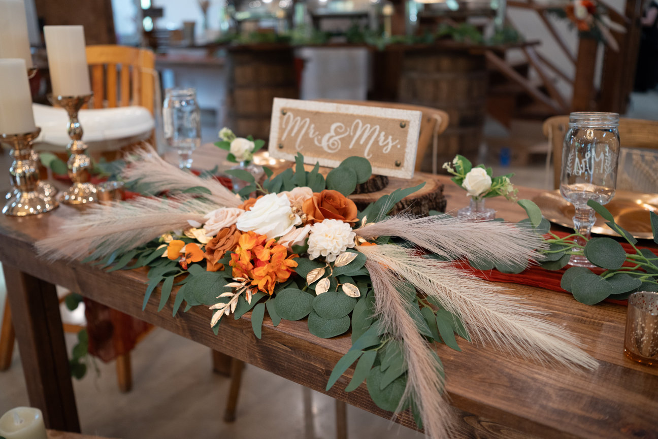 Wedding reception table with floral centerpiece and rustic decor.