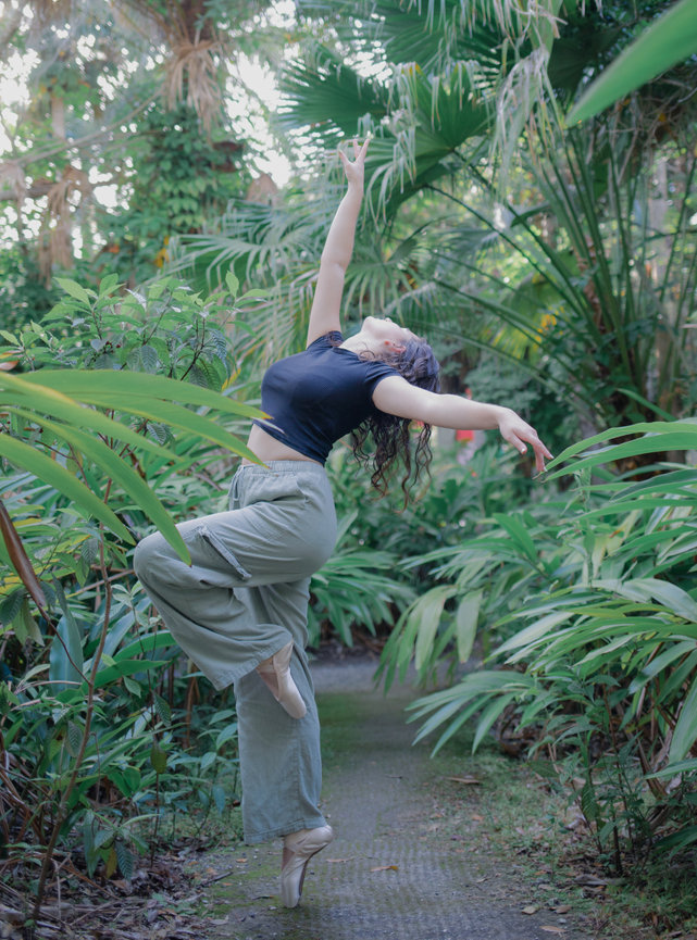 Dancer posing in garden surrounded by lush greenery
