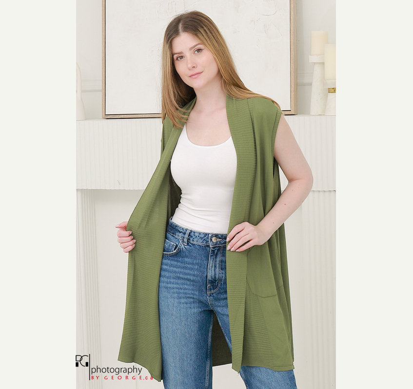 Model wearing green sleeveless cardigan over tank top and denim jeans in spring summer fashion photoshoot.