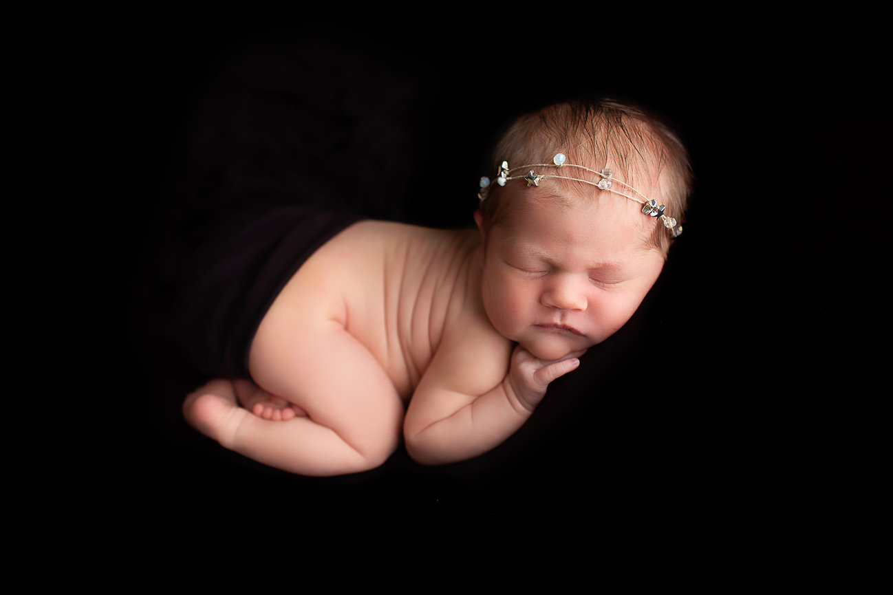 Newborn baby girl in bum up pose on black fabric during newborn photoshoot with newborn photographer Dreamworks Photography in Kansas City kansas