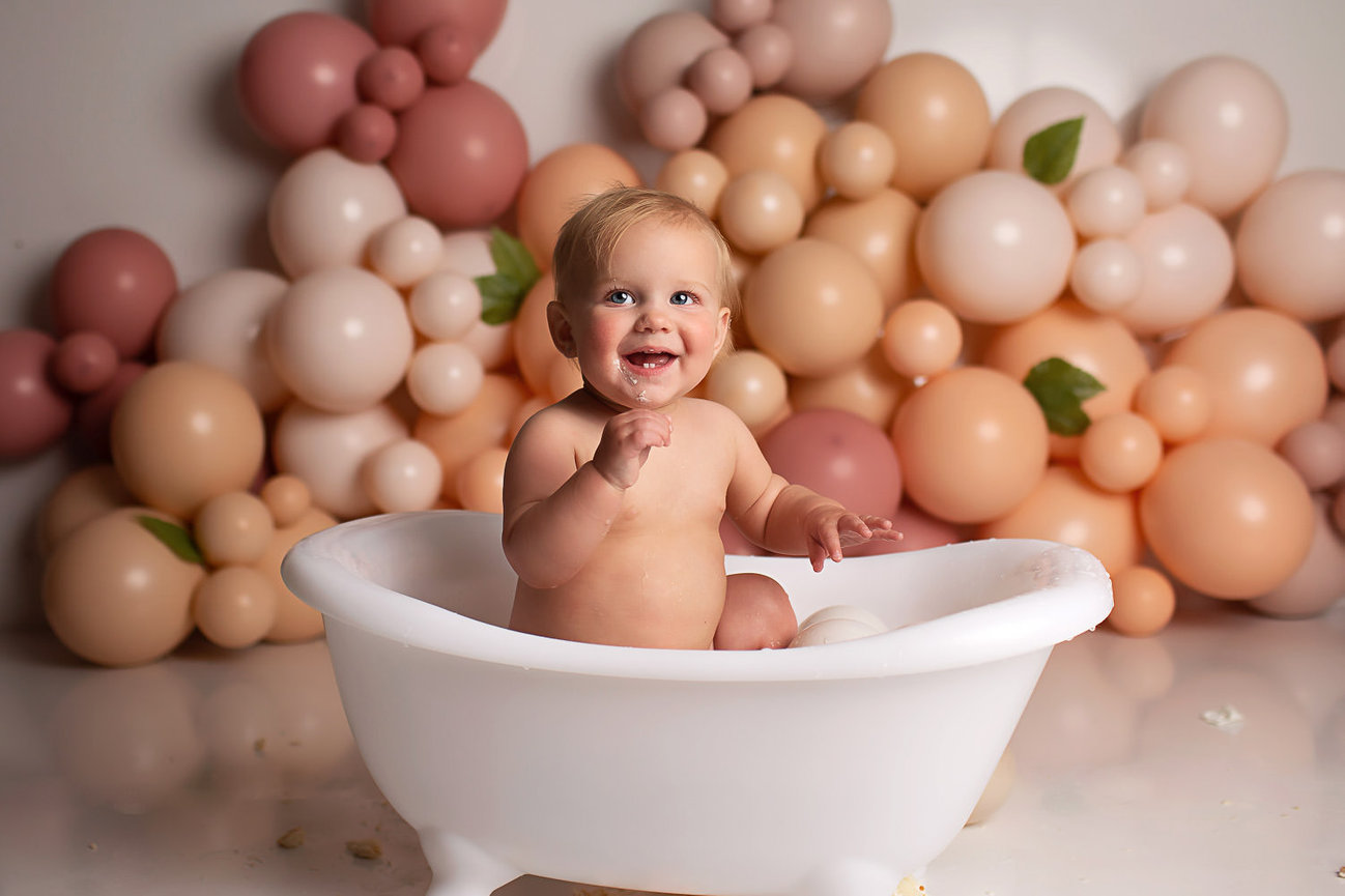 Baby girl smiling in baby bath tub after cake smash photography session with cake smash photographer Dreamworks Photography in Kansas City baby photography studio