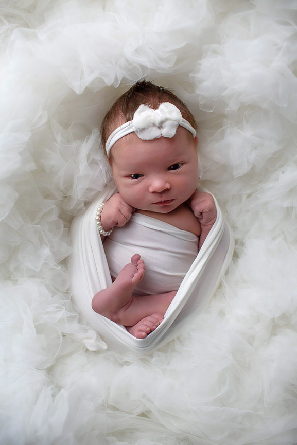 newborn baby girl curled up awake with eyes open on soft white fabric during newborn photoshoot with kansas city newborn photographer Dreamworks Photography