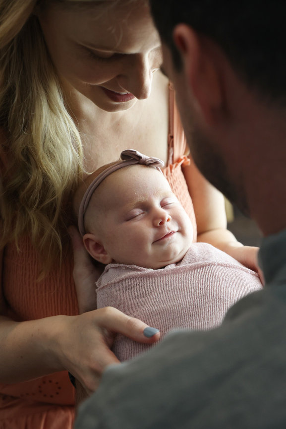 baby smiling for photo with parents