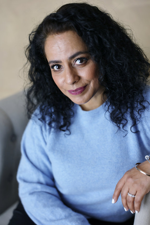 Portrait of a woman with curly black hair wearing a light blue sweater and silver jewelry.authentic photos for my business and website