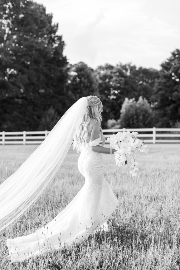 Bride walking with bouquet in a field at Pursell Farms in Alabama. Alabama wedding photography by Heather Durham.