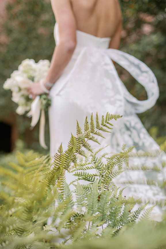 Bride in Monique Lhuillier gown surrounded by fern. Wedding photography by Heather Durham.