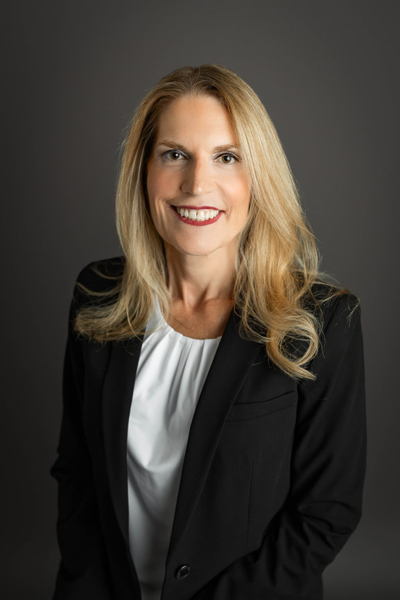 Professional business headshot of smiling woman in studio with neutral background
