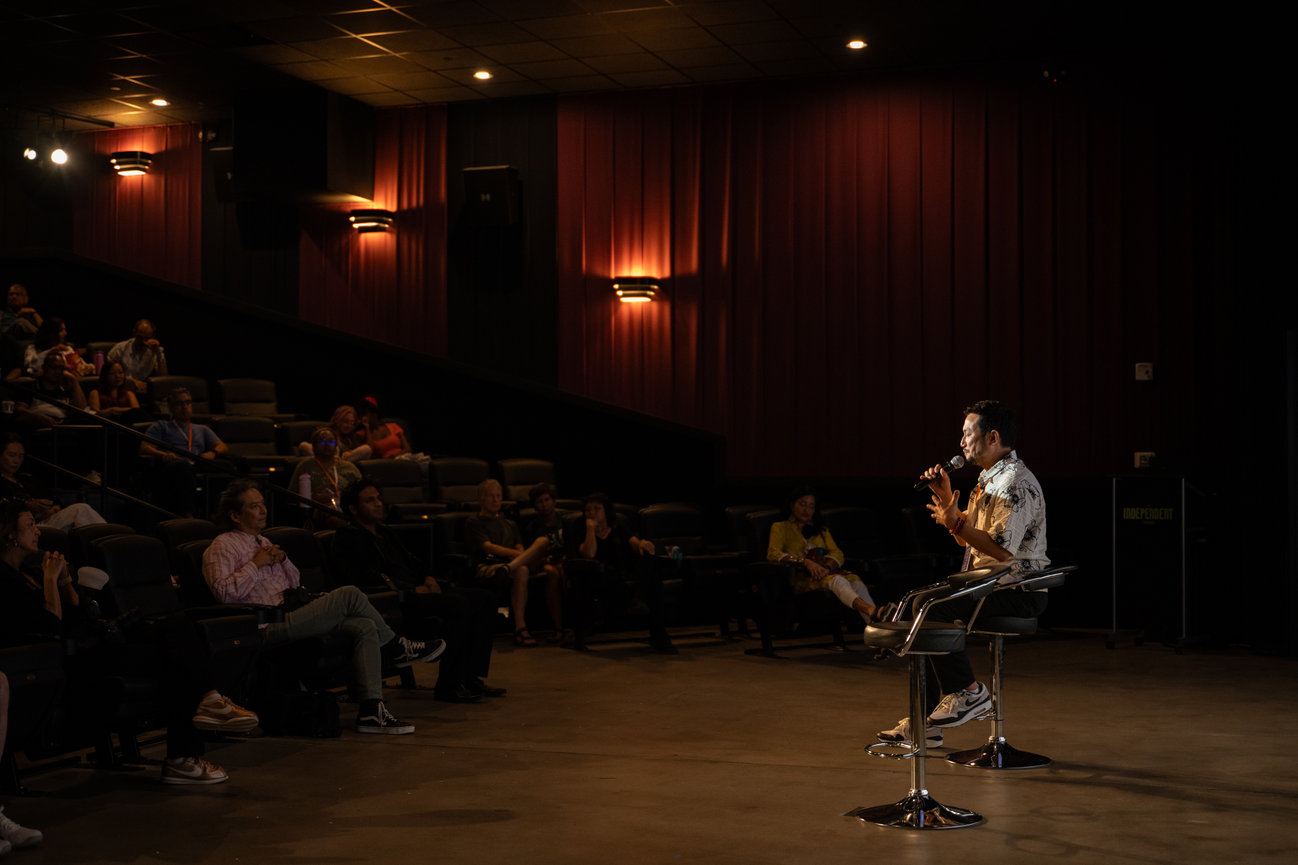 Man speaking into a microphone during a theater audience talk in a dimly lit auditorium HBO director Eugene Yi for The A List Documentary speaks at Independent Picture House