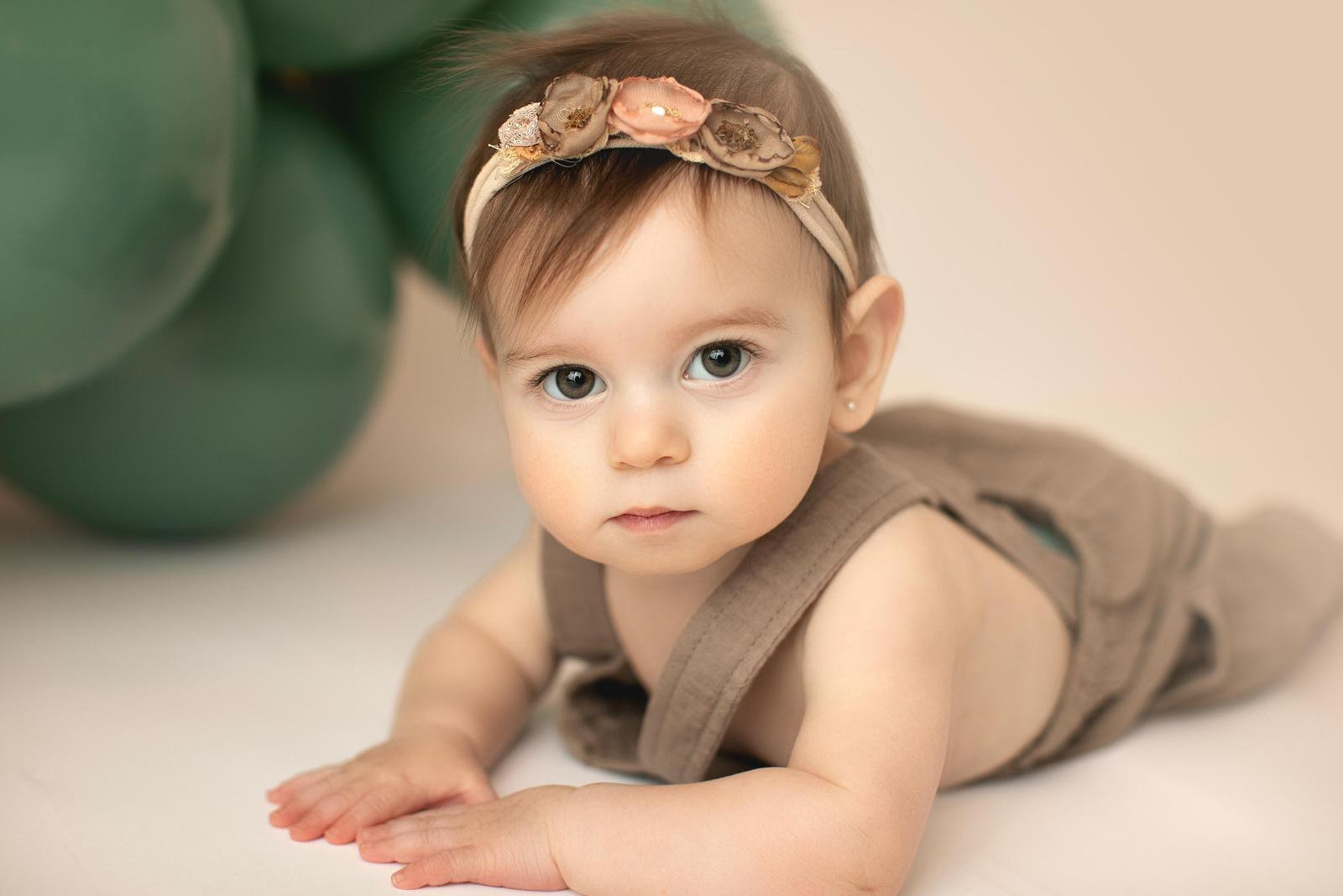 Baby lifting their head in a brown romper