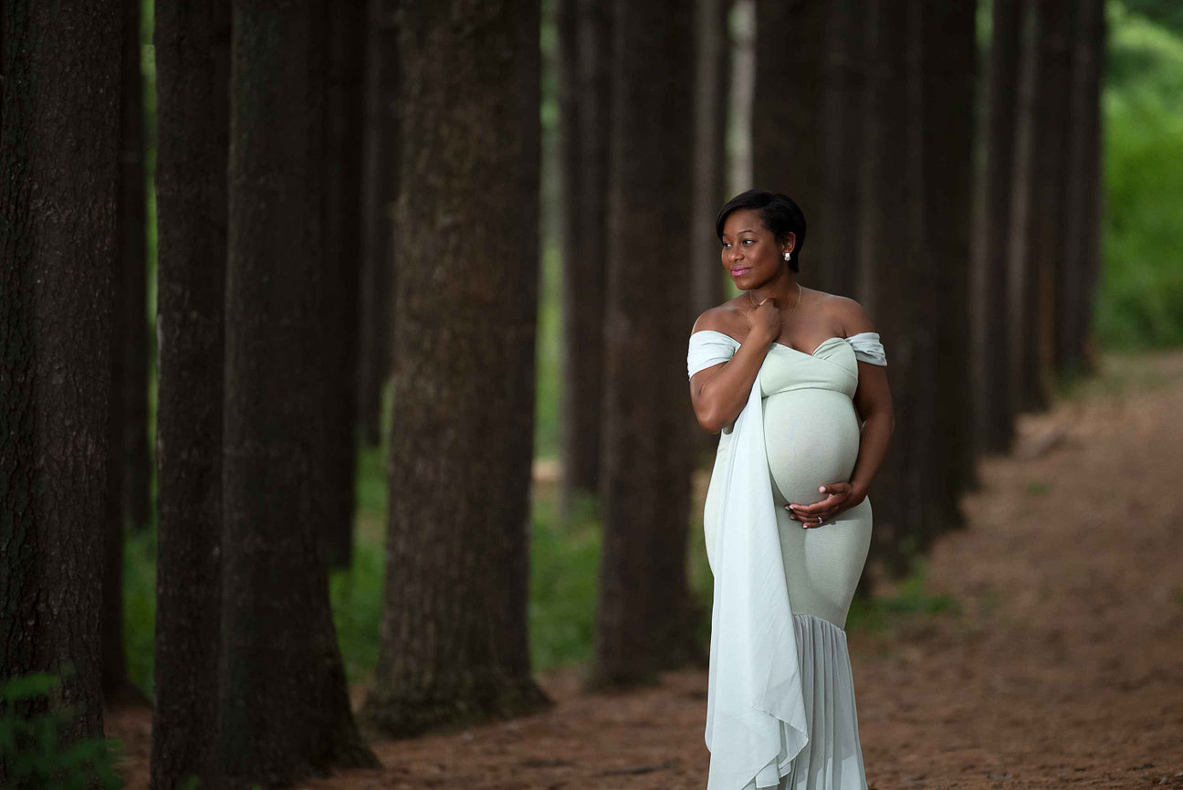 beautiful new mom wearing a light green dress in the woods