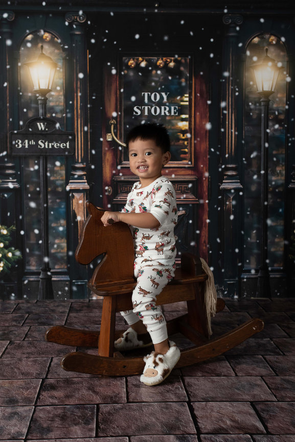 A little boy on a rocking horse in front of a toy store
