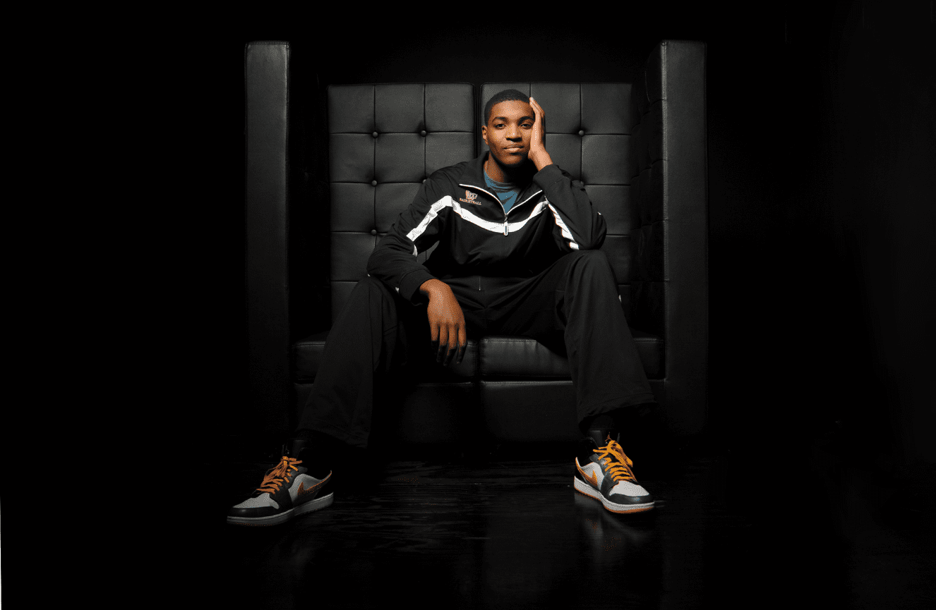 An African American basketball player in his training gear poses contemplatively.