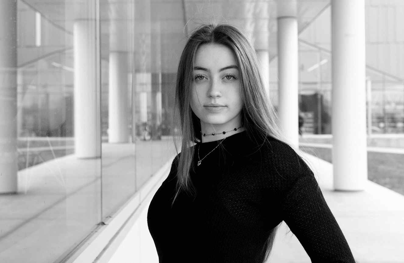 A confident looking high school senior standing among building pillars.