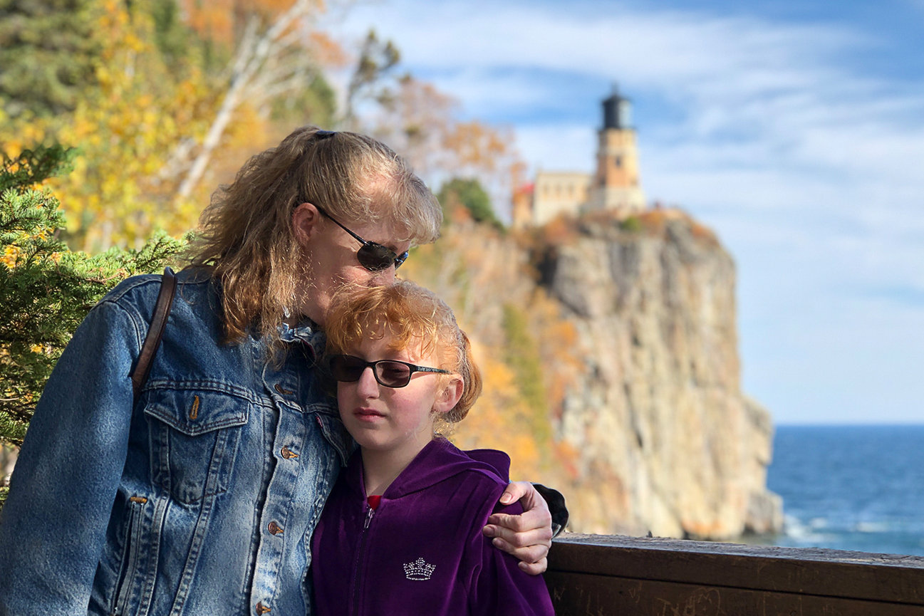 Mother with child near a lighthouse on a cliff