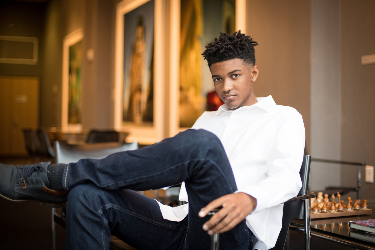 Teenage boy in a white button down shirt and jeans in the lobby of a hotel posing for senior pictures in Columbus OH.