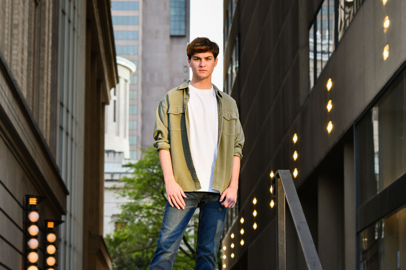Dark haired teenage boy standing at the top of a staircase in an urban setting for senior pictures in Columbus.