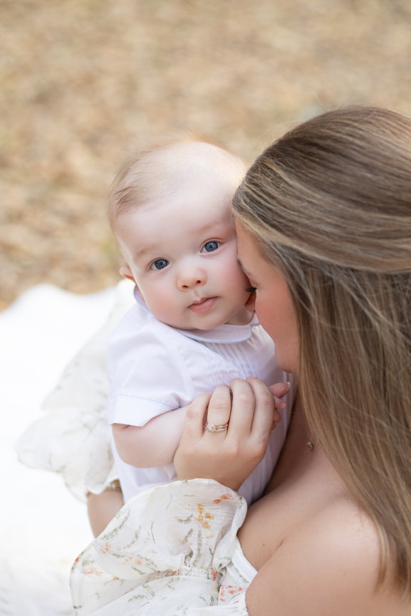 Mother holding baby and kissing its cheek outdoors